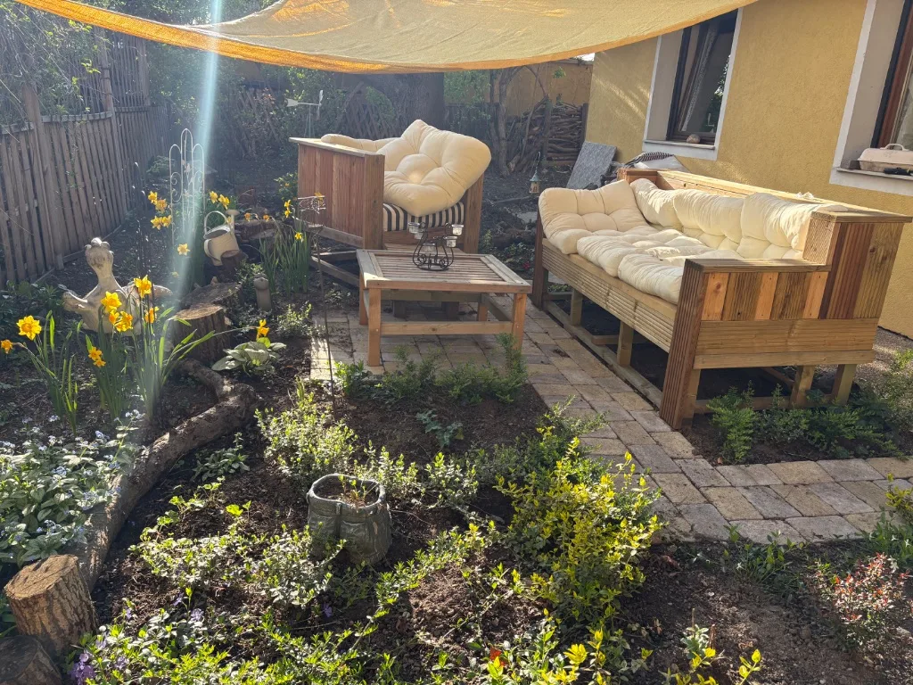 Therapie-Garten Thomas Laggner – Holz-Lounge mit Sonnensegel und Frühlingsblumen