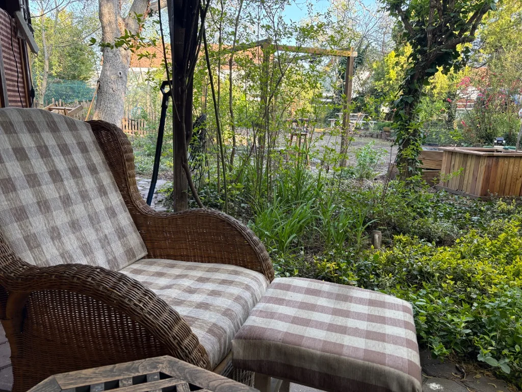Gemütliche Sitzecke im Therapie-Garten – Rattan-Sessel mit Hocker im Grünen